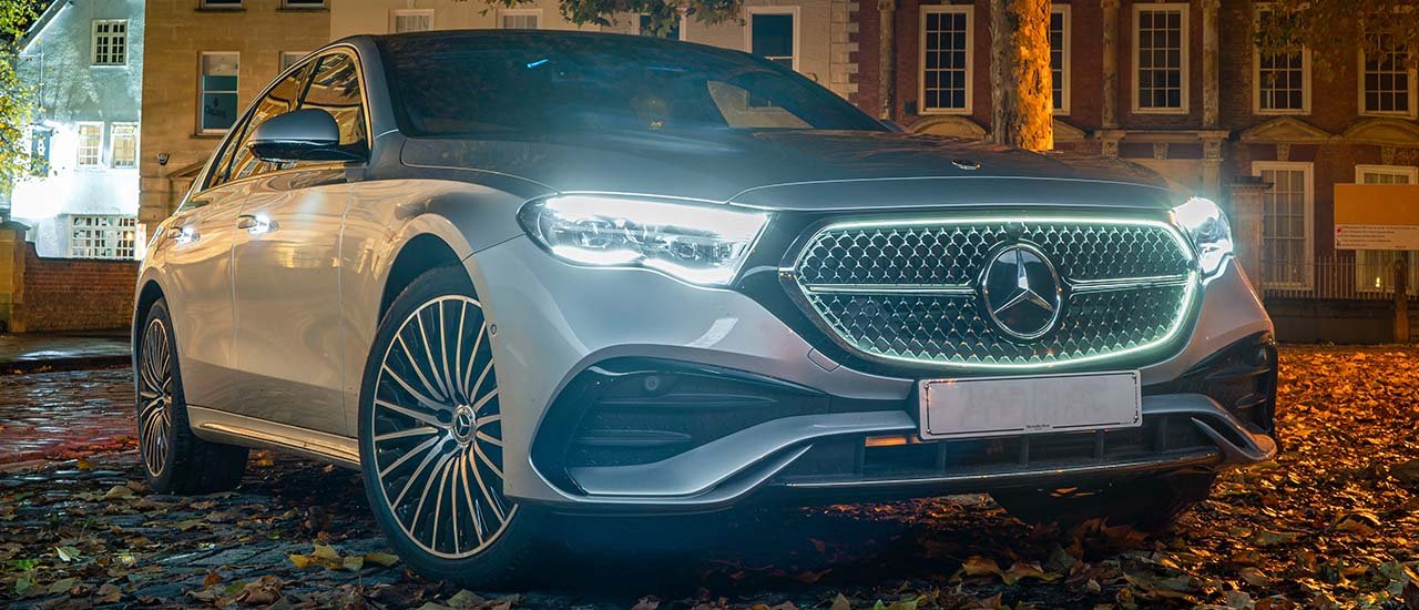 Stunning Mercedes-Benz E-Class illuminated at night with bright LED headlights, reflecting the stylish design for a night out in London.